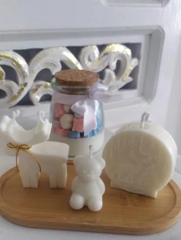 Velas con forma de oso, rostro y círculo sobre una bandeja de madera